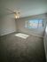 Bright, spacious bedroom with plush carpet, elegant ceiling fan, and large window offering scenic views.