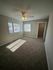 Bright and cozy bedroom with plush carpeting, large windows, and a ceiling fan, offering a serene and inviting atmosphere.