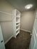 Spacious walk-in closet with white shelving and ample hanging space, perfect for organized living.