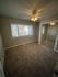 Bright bedroom featuring plush carpet, ample natural light through large windows, and convenient mirrored closet doors.
