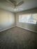 Bright, freshly-painted room with plush carpeting and large window overlooking a serene view, perfect for a cozy bedroom setup.