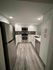 Contemporary kitchen with sleek stainless steel appliances, elegant white cabinetry, and chic hardwood floors.