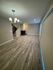 Spacious open-concept living area with sleek wood flooring, modern chandelier, and ambient lighting.
