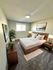 Inviting bedroom with modern decor, featuring a cozy bed with crisp white linens, accent plants, and elegant wooden furniture.
