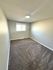 Cozy bedroom with plush carpeting, minimalist design, and a bright window for natural light.