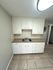 Bright kitchen featuring sleek white cabinetry, elegant tile flooring, and a stainless steel sink, perfect for modern living.