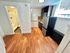 Charming apartment kitchen with sleek stainless steel appliances, warm wood flooring, and a cozy bathroom entrance.