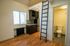 Charming studio apartment with a modern kitchenette, hardwood floors, and a loft ladder beside a cozy bathroom.