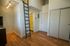 Chic studio apartment with modern loft ladder, stylish wooden flooring, and bright lighting.
