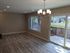 Bright and airy living room with elegant wood flooring, modern chandelier, and large sliding glass doors opening to a serene backyard.