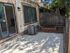 Charming patio with sliding glass door, perfect for relaxing in the shade, featuring a small garden area and privacy fencing.