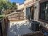 Charming outdoor patio with sliding glass doors, surrounded by a wooden fence and lush greenery, ideal for relaxation and entertaining.