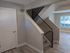 Modern apartment interior featuring a sleek staircase with black railings, light wood flooring, and a large window for natural light.