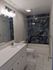 Elegant bathroom with modern vanity, chic tile flooring, and luxurious stone-tiled bathtub area.