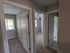 Bright apartment hallway with multiple doorways leading to cozy carpeted bedrooms, enhanced by natural light from large windows.