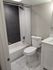 Elegant bathroom featuring modern white fixtures, a sleek bathtub with a glass curtain, and stylish marble floor tiles.