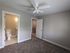 Bright bedroom with plush carpet, en-suite bathroom, and a ceiling fan, offering comfort and modern elegance.