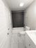Sleek modern bathroom featuring elegant marble floor tiles, a pristine white bathtub, and a contemporary vanity.