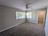 Bright, spacious bedroom with plush carpet, large windows offering natural light, and a ceiling fan for comfort.