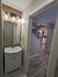 Chic bathroom with modern lighting leading into a stylish kitchen featuring sleek stainless steel appliances and elegant wood flooring.