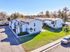 Charming apartment complex with white exteriors, lush green lawns, and ample parking in a serene neighborhood setting.