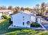 Charming apartment complex with well-maintained lawns, inviting pathways, and ample parking, surrounded by lush greenery on a bright sunny day.