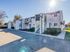 Charming apartment complex with contemporary design, featuring outdoor staircases and lush greenery under a clear, sunny sky.