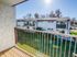 Charming apartment balcony view showcasing a sunny, serene landscape with manicured lawns and modern nearby buildings.