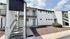 Charming apartment exterior with contemporary design, featuring white walls, stylish gray doors, and outdoor stairway access.