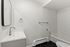 Modern bathroom featuring a sleek white vanity, chrome fixtures, and a stylish tiled bathtub.