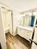 Bright and modern bathroom featuring elegant vanity with marble countertop, luminous lighting, and sleek wood flooring.
