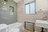 Modern bathroom with elegant green subway tiles, a sleek white bathtub, and a stylish sink under a bright window.