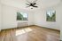 Bright and airy bedroom with elegant wood flooring, stylish ceiling fan, and large windows with garden views.