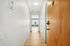 Inviting apartment hallway entrance with sleek wooden flooring and soft lighting leading into a bright living space.
