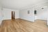 Spacious apartment with elegant hardwood floors and fresh white walls, featuring an open entryway and a cozy nook with overhead lighting.