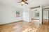 Bright and airy room with elegant hardwood flooring, ceiling fan, and large mirrored closet doors overlooking a scenic outdoor view.