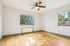Bright and airy room with polished hardwood floors, large windows offering scenic views, and a modern ceiling fan.