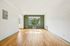 Inviting living room with elegant hardwood floors, a large sunlit window, and a stylish accent wall.