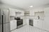 Contemporary kitchen with sleek stainless steel appliances, pristine white cabinetry, and elegant hexagonal floor tiles.