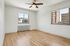 Bright and spacious bedroom with hardwood floors, large windows offering city views, and a ceiling fan for comfort.