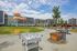 Vibrant urban park view featuring colorful sculptures, open green space, and recreational facilities, surrounded by modern apartment buildings.