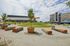 Vibrant urban park featuring lush green mounds, colorful benches, and modern art installations, nestled between contemporary buildings.