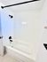 Pristine bathroom featuring a sleek white bathtub, modern black fixtures, and elegant tile walls.