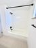 Elegant bathroom featuring a pristine white bathtub with modern black fixtures and sleek tile work.