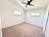 Bright and airy bedroom with soft carpeting, modern ceiling fan, and ample natural light from dual windows, offering a serene retreat.