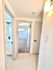 Bright hallway with modern light fixtures leading to carpeted bedroom and sleek bathroom, showcasing stylish finishes.