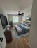 Inviting bedroom with modern decor featuring a sleek ceiling fan, stylish artwork, and abundant natural light from a large window.