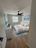 Bright and modern bedroom with minimalist decor, featuring a cozy bed, sleek furniture, and a ceiling fan enhancing comfort.