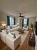 Inviting living room with modern white sofas, vibrant blue accents, and elegant wooden furniture, perfect for relaxing and entertaining.