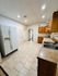 Bright and spacious kitchen with modern appliances, wooden cabinetry, and elegant tiled flooring, offering a welcoming entrance through an archway.